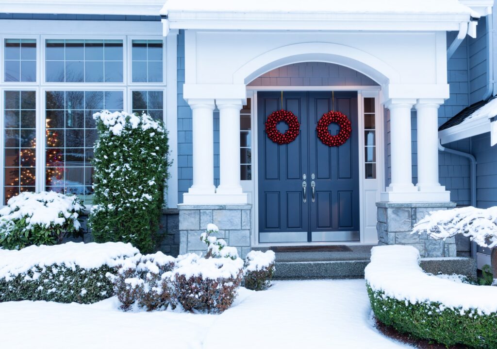 snow covered home with blue front door